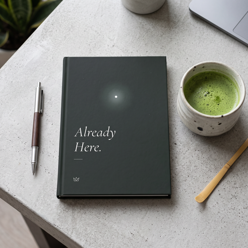 Forest-green Already Here journal on a stone table next to a cup of matcha and a pen