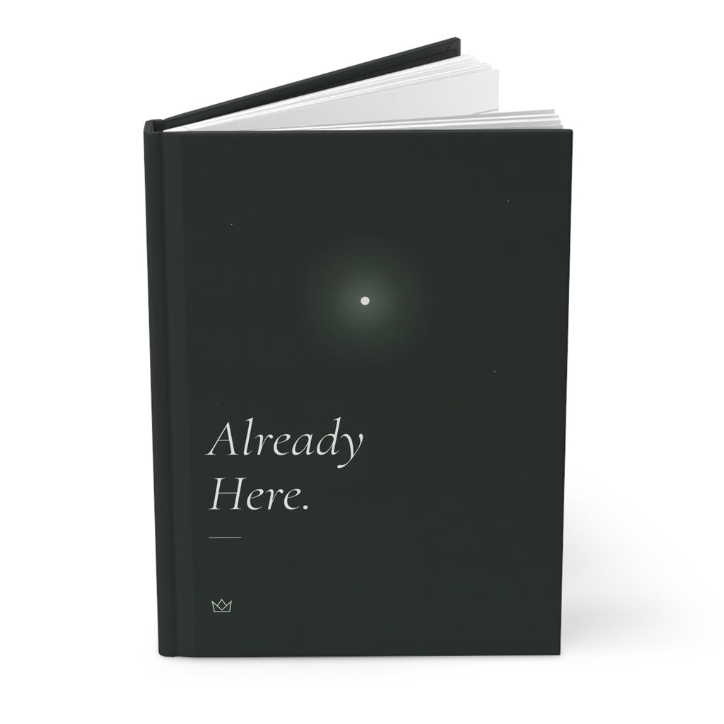 Already Here hardcover journal standing upright with a pen on top, showing the glowing star and dark spine