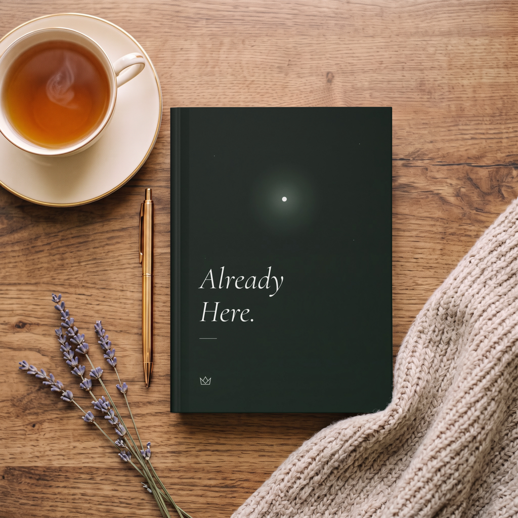 Already Here journal on a wooden table with a cup of tea, dried lavender and a knit sweater