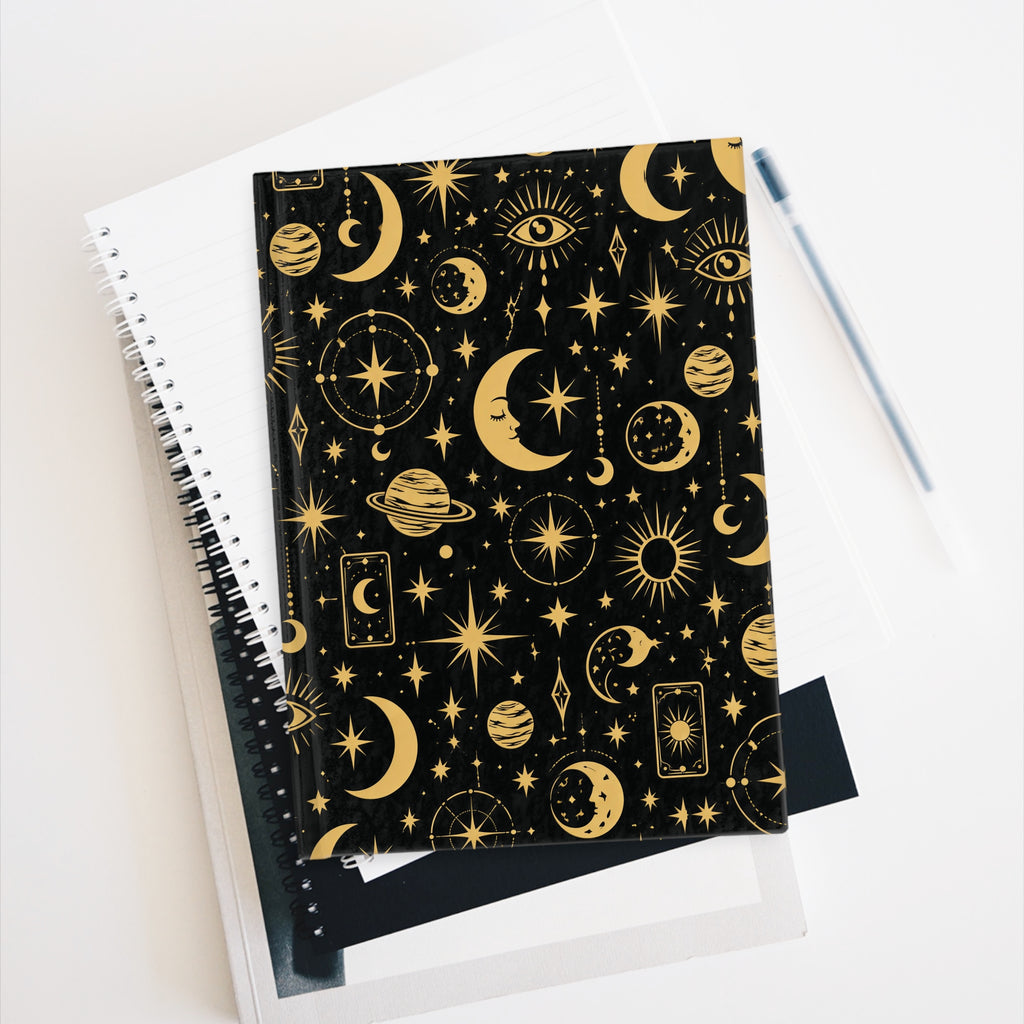 Celestial Mystic journal resting against a notebook with a pen alongside