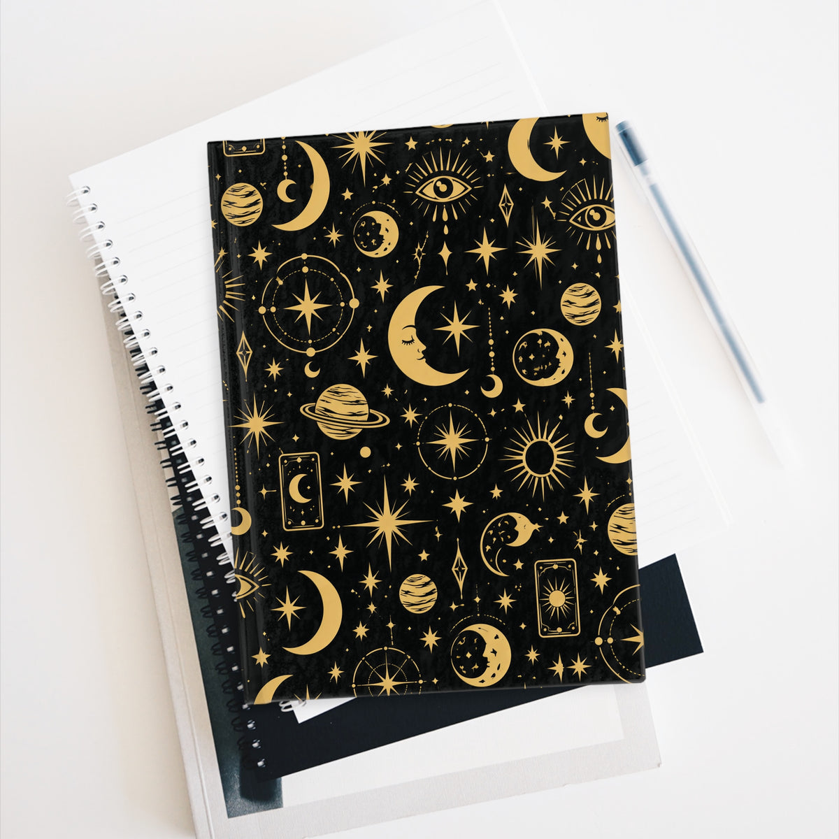 Celestial Mystic journal resting against a notebook with a pen alongside