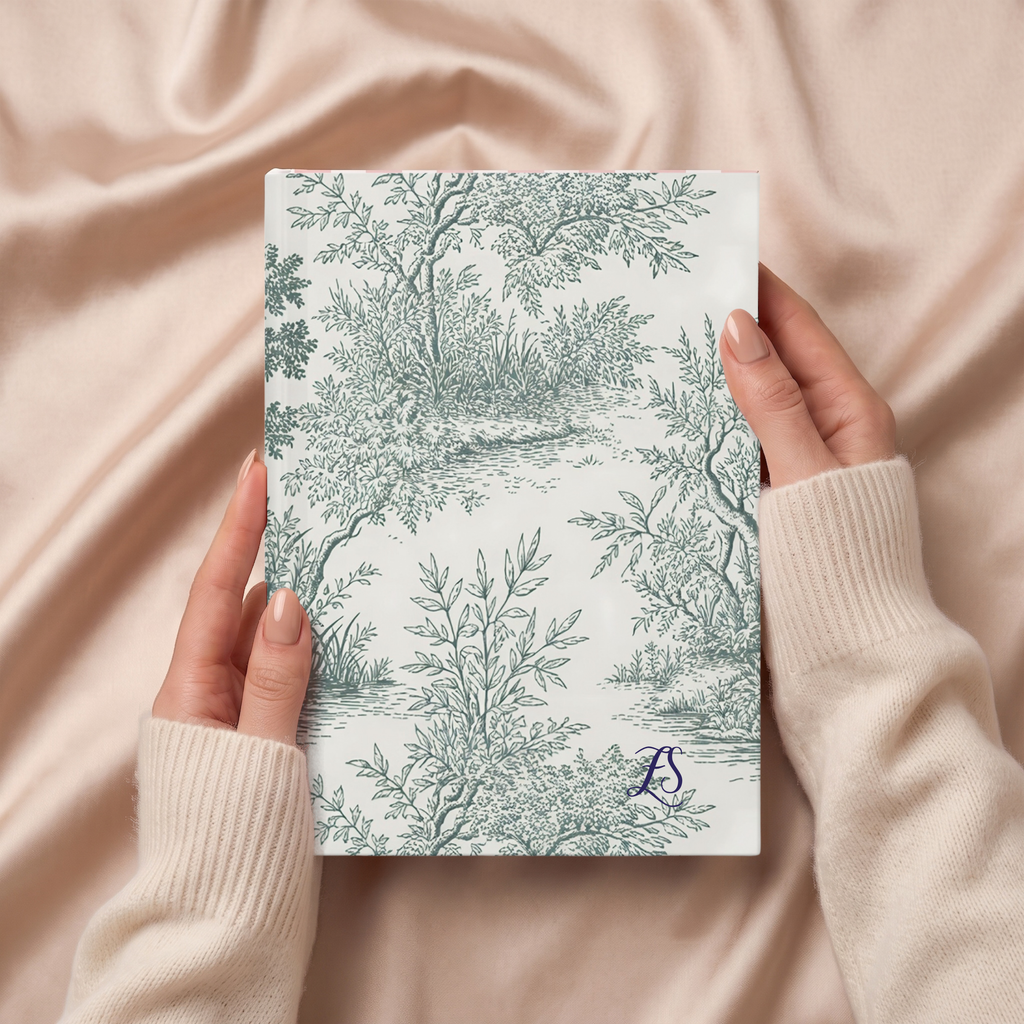 Hands holding the green Toile de Jouy forest journal on pink satin