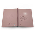 My Most Successful Life journal laid open flat, showing the full wraparound dusty rose cover: back with a personalized name, spine with FIELD NO. 13, and front with a glowing star