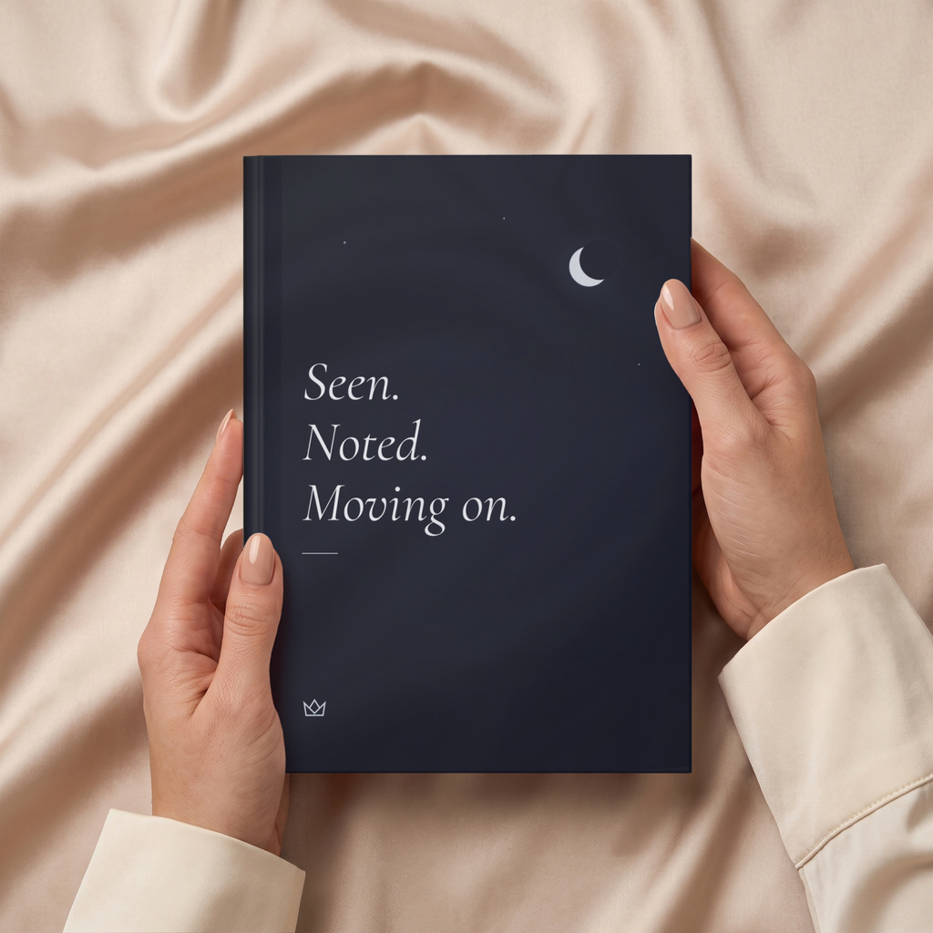 Hands holding the night-blue Seen. Noted. Moving on. journal over soft beige fabric