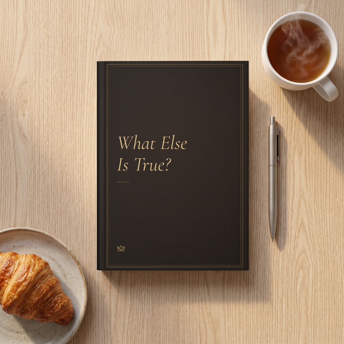 What Else Is True? journal on a breakfast table with a croissant, a cup of tea and a pen
