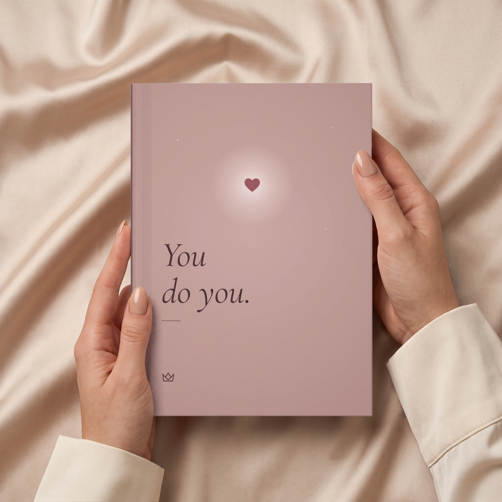 Hands holding the personalized You Do You journal over soft beige fabric