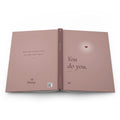 You Do You journal laid open flat, showing the full wraparound dusty rose cover: back with a personalized name, spine with FIELD NO. 12, and front with a glowing heart